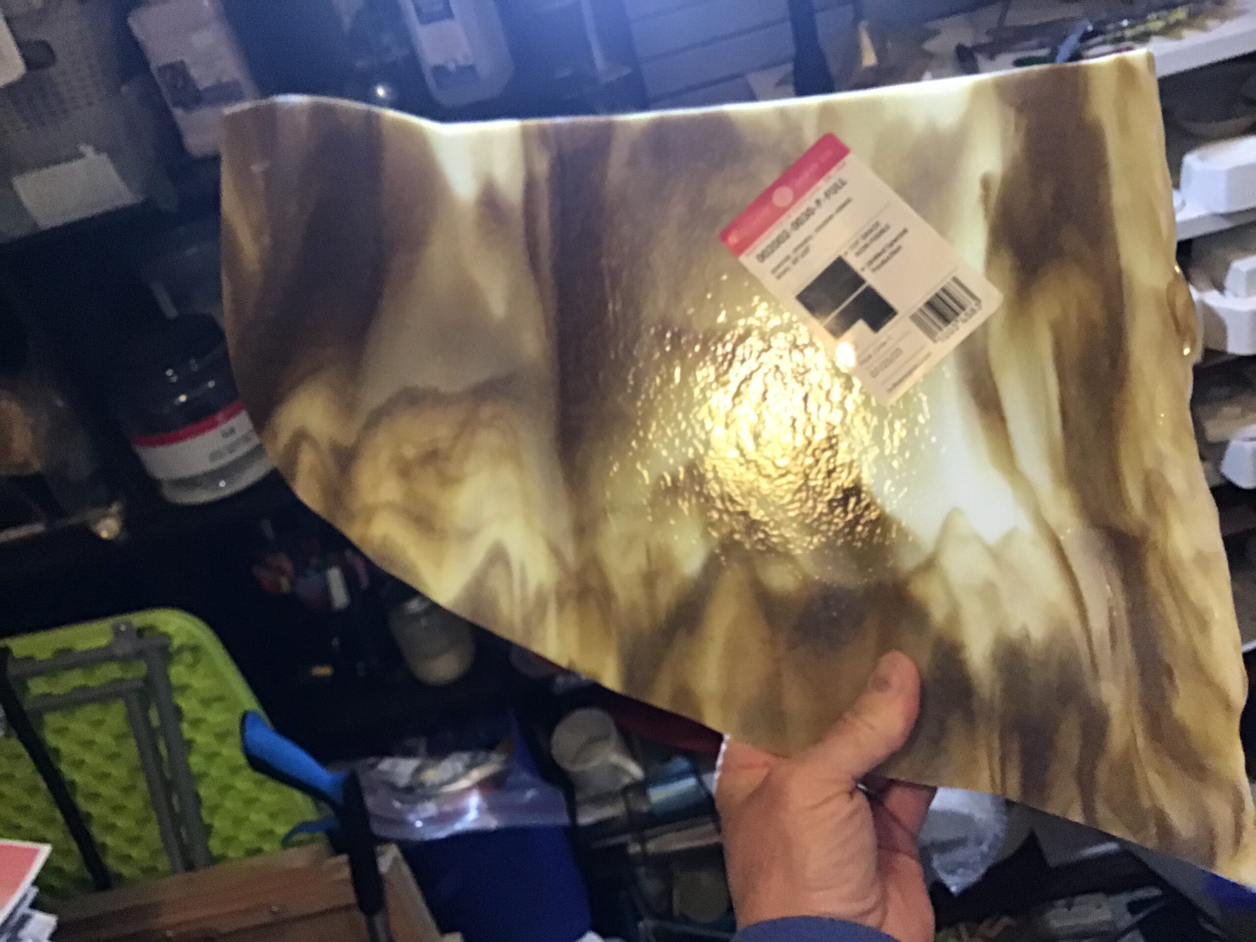 Holding a marbled brown sheet of stained glass up to the light.