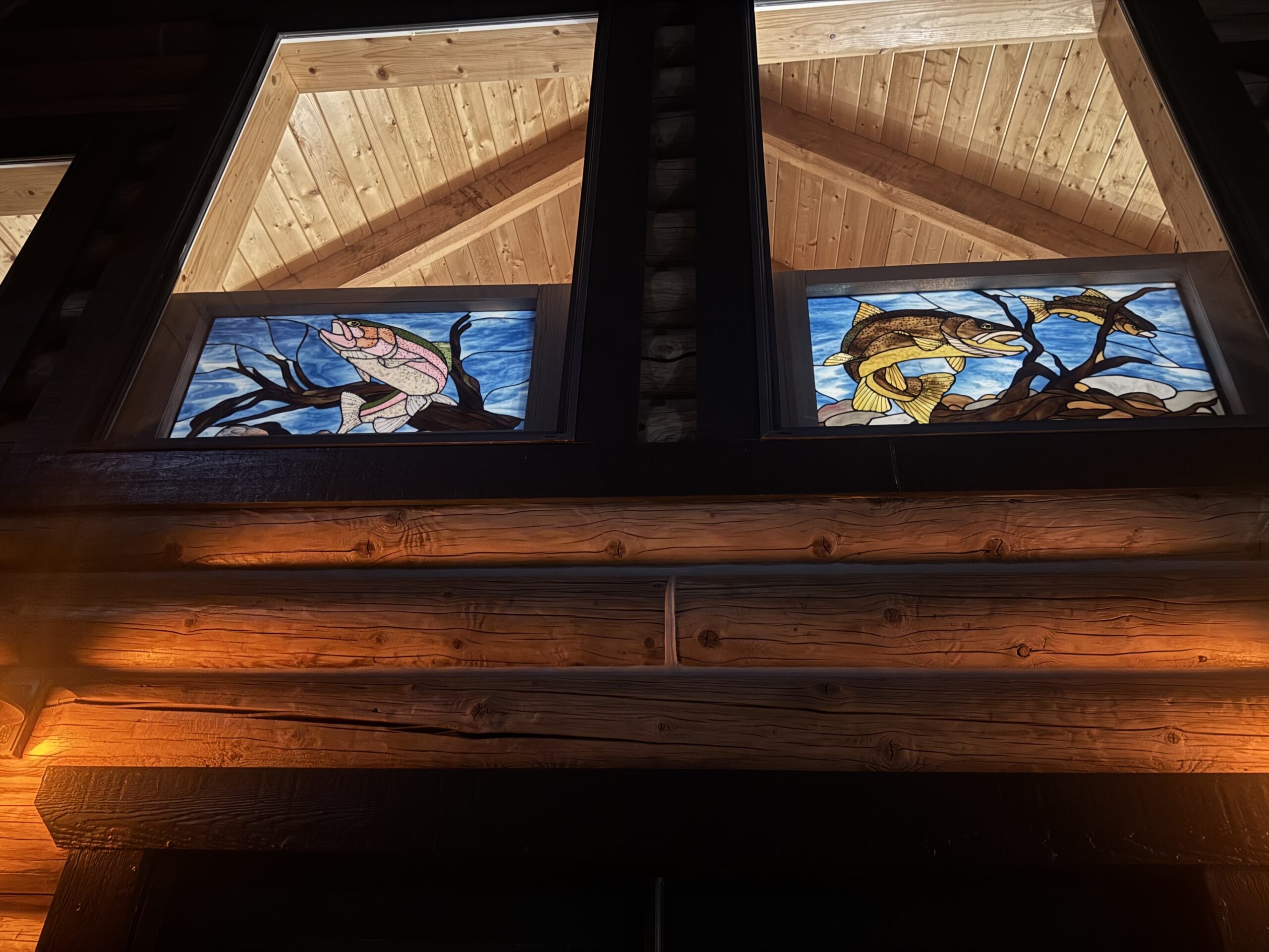 Stained glass panels glowing at night from the exterior front view.
